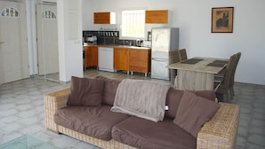 A compact living space with a kitchenette, a dining area with a table and chairs, and a sofa. - Blue Hills Residence with Scenic Views (Sampzon)