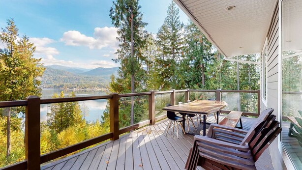 A wooden deck with a table and chairs overlooking a lake and forest. - Okanagan - IKES Retreat (Kootenay Boundary)