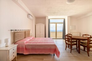 A bedroom with a bed, bedside table, and a view of the sea through a door. - Con vista mare, terrazza, aria condizionata (Castelsardo)