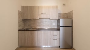 A compact kitchen with light wood cabinets, a stainless steel refrigerator, and a tiled backsplash. - Apartment with sea view and terrace (Castelsardo)