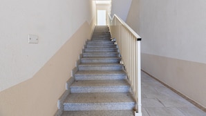 A staircase with a handrail, carpeted steps, and a light switch on the wall. - Apartment with sea view and terrace (Castelsardo)