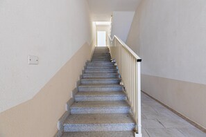 Eine Treppe mit Handlauf, Teppichstufen und einem Lichtschalter an der Wand.