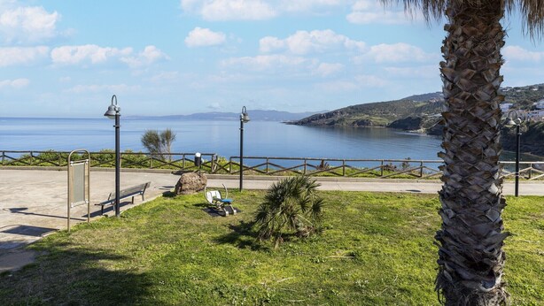 A coastal park with a bench, a lamp post, and a palm tree. - Apartment with sea view and terrace (Castelsardo)