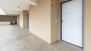 A hallway with numbered doors, a tiled floor, and a ceiling with recessed lighting. - Apartment with sea view and terrace (Castelsardo)