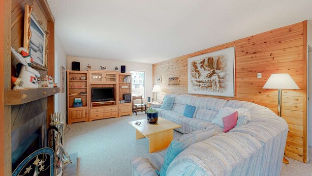 Una sala de estar acogedora con pared de madera, un sofá, una mesa de centro y un mueble para televisión.