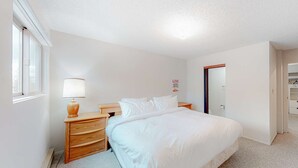 Un dormitorio con cama, mesita de noche, lámpara, cómoda de madera y armario.