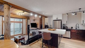 Una cocina moderna con una isla central, vigas de madera y un ventanal grande.