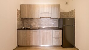 Una cucina compatta con mobili in legno, un lavello in acciaio inox e un frigorifero nero.