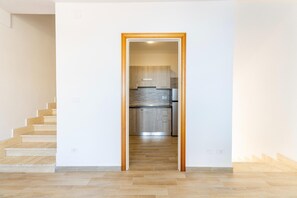 A hallway leading to a kitchen with wooden cabinets and a stainless steel refrigerator. - Apartment with sea view and terrace (Castelsardo)