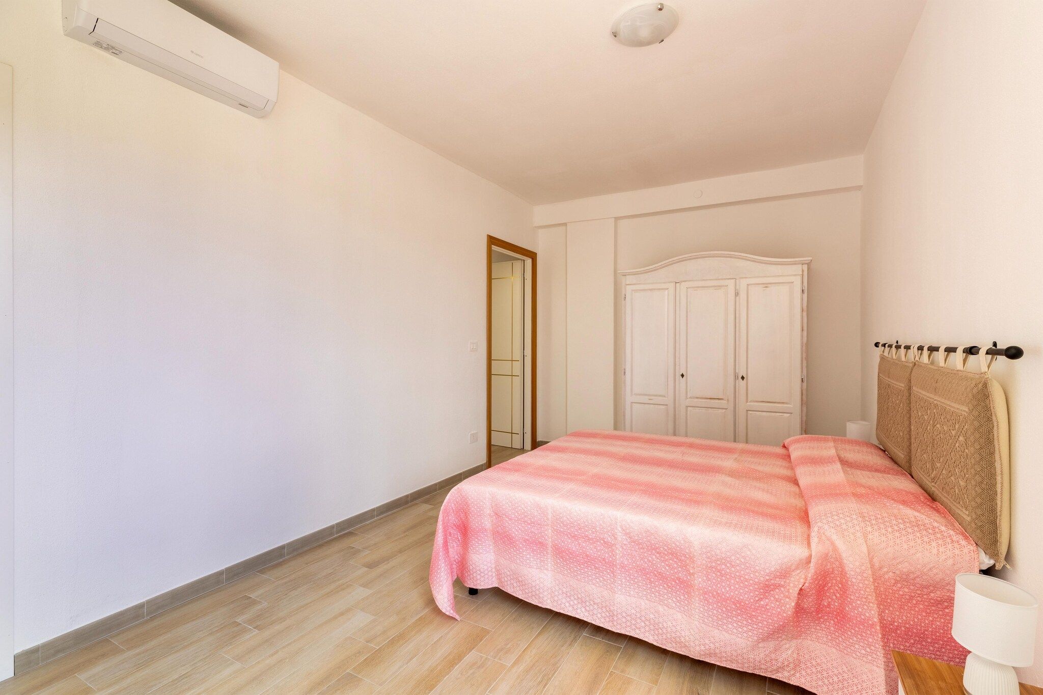 A bedroom with a bed, a wardrobe, and a ceiling light.