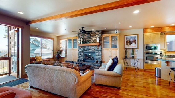 A spacious living area with a fireplace, comfortable seating, and a kitchen with modern appliances. - Okanagan - Northern Star (Kootenay Boundary E)
