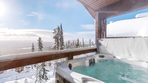 A hot tub with a wooden deck and a view of snow-covered trees and mountains. - Okanagan - Powder View 5 (Beaverdell)
