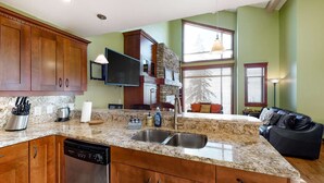 A kitchen with granite countertops, wooden cabinets, a dishwasher, and a stone backsplash. - Okanagan - Powder View 5 (Beaverdell)