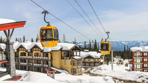 A ski resort with yellow cable cars, a lodge with a snow-covered roof, and a mountainous backdrop. - Okanagan - Powder View 5 (Beaverdell)