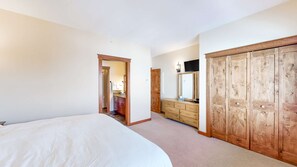 Un dormitorio con cama, cómoda, espejo y armario.