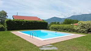 A rectangular swimming pool with a metal ladder, surrounded by a brick border and a stone pathway leading to it. - Belmonte Holiday Apartment (Brezzo di Bedero)