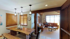 A spacious living area with a wooden dining table, leather sofas, and a large window. - Okanagan - Rockridge 375 Snow Escape (Kootenay Boundary E / West Bo)