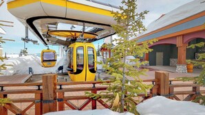 A yellow cable car at a station with a wooden fence and snow-covered ground. - Okanagan - Rockridge 375 Snow Escape (Kootenay Boundary E / West Bo)