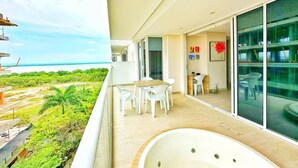 Een balkon met uitzicht op de oceaan, een zithoek met stoelen, en een ruime badkuip.