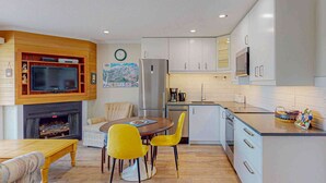 Une cuisine compacte avec un coin repas, un téléviseur encastré et une horloge au mur.