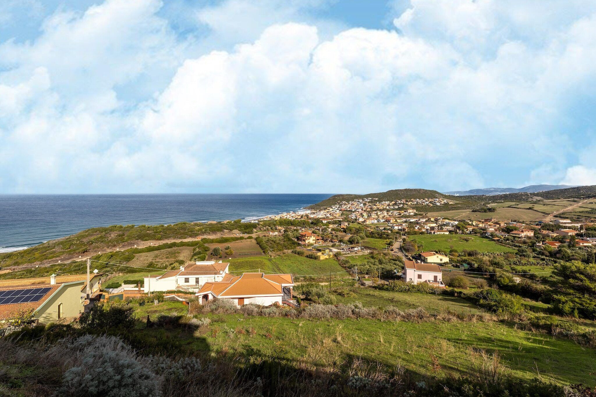 Une ville côtière avec des maisons, une vue sur la mer et un paysage vallonné.