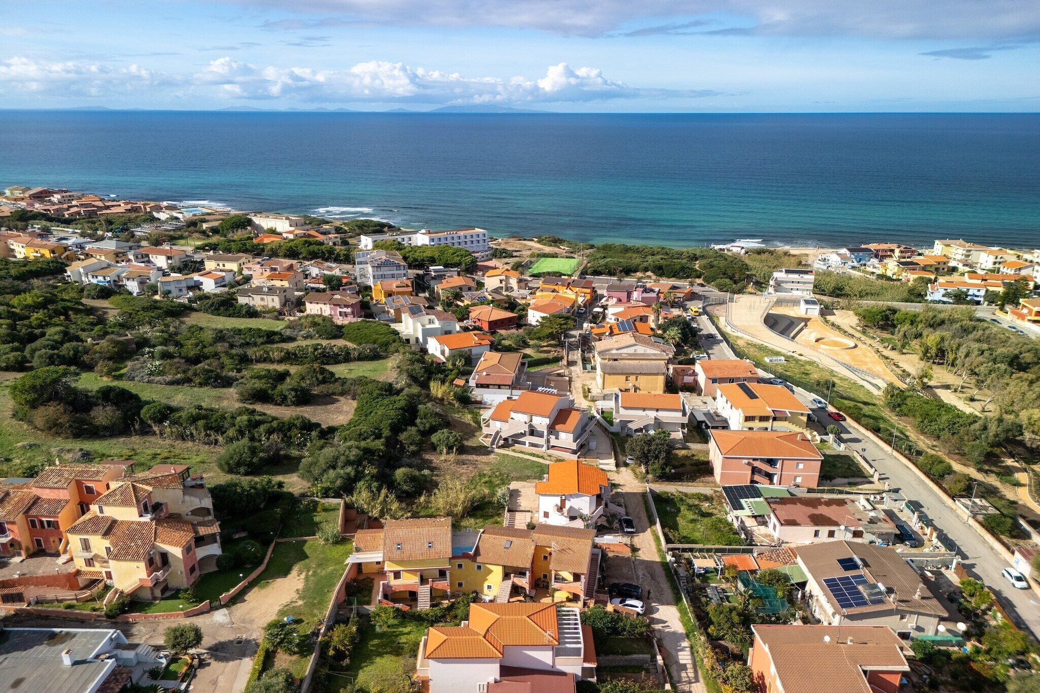 An aerial view of a coastal town with houses, roads, and a beach.
