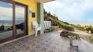 Un patio con vista al océano, un muro de piedra y una silla blanca.