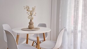 Una mesa redonda para comer con un florero, rodeada de sillas blancas.