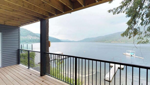 A wooden deck with a railing overlooking a calm lake with boats, surrounded by hills. - Okanagan - Sunshine Beach (Christina Lake)