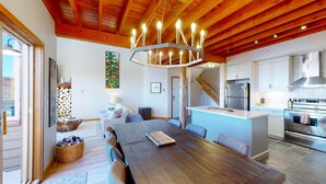 A spacious kitchen with modern appliances, a dining area with a wooden table, and a cozy living space with a fireplace. - Okanagan - Snowy Creek 10 (Beaverdell)
