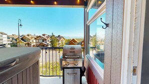 Un balcón con una parrilla y vistas a una zona residencial.