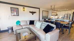 Una sala de estar moderna con un sofá seccional, una mesa de centro y un comedor con una mesa y sillas de madera.