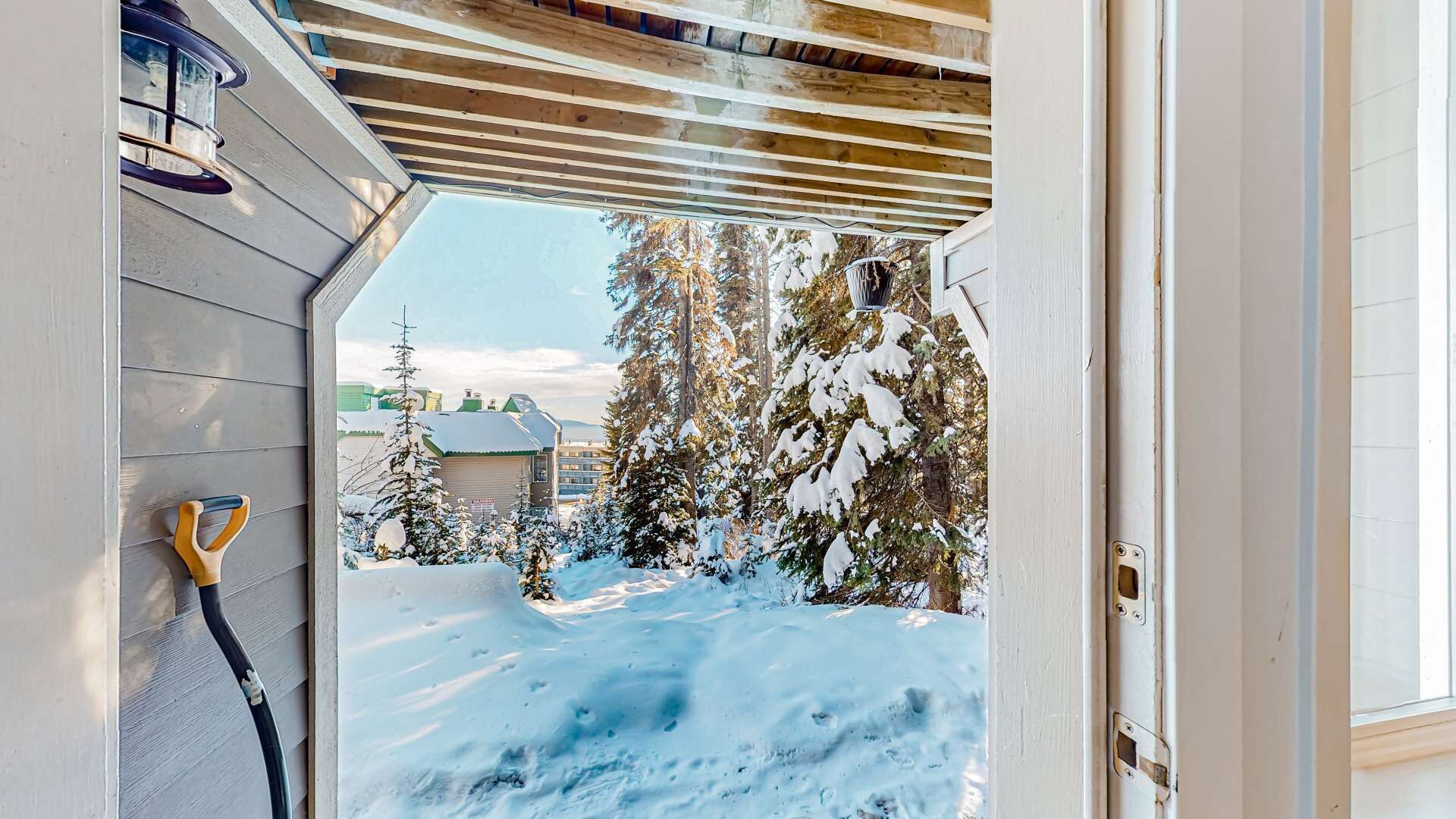 A wooden exterior wall with a window, a door, and a snow-covered ground.
