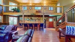 Un chalet spacieux à deux étages, doté d’un bar, de sièges en cuir et de planchers en bois.