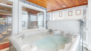 Un espace de bien-être comprenant un jacuzzi, un plafond en bois et une vue sur l’intérieur.