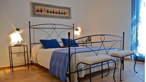 Ein Bett mit Metallgestell, Bettwäsche in Blau und Weiß sowie zwei Nachttische mit Lampen.