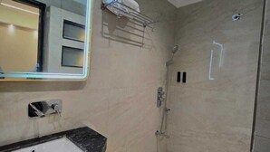 Un baño moderno con un lavabo negro, inodoro blanco y ducha con mampara de vidrio.