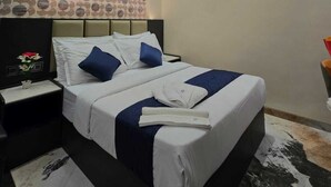 Una habitación de hotel moderna con una cama bien hecha, un cabecero con un diseño circular y una mesita de noche con un jarrón de flores.