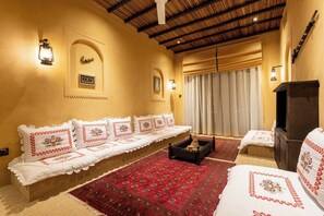 A cozy room with a sofa set, a TV cabinet, and a red patterned rug. - Heritage 2-bedroom Apartment (Dubai)