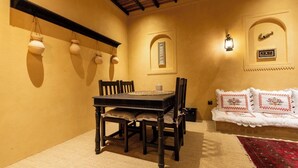 A dining area with a table and chairs, a hanging light fixture, a wall-mounted clock, and a decorative wall panel. - Heritage 2-bedroom Apartment (Dubai)