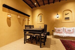 A dining area with a table and chairs, a hanging light fixture, a wall-mounted clock, and a decorative wall panel. - Heritage 2-bedroom Apartment (Dubai)