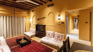 A cozy room with a bed, a TV, a fireplace, and a hallway leading to another room. - Heritage 2-bedroom Apartment (Dubai)