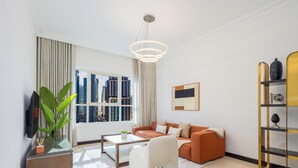 A modern living room with a sofa, coffee table, and a bookshelf. - LUX The 02 Residences JLT Suite (Dubai)
