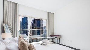 A hotel room with a large window, a bed, a desk, and a chair. - LUX The 02 Residences JLT Suite (Dubai)