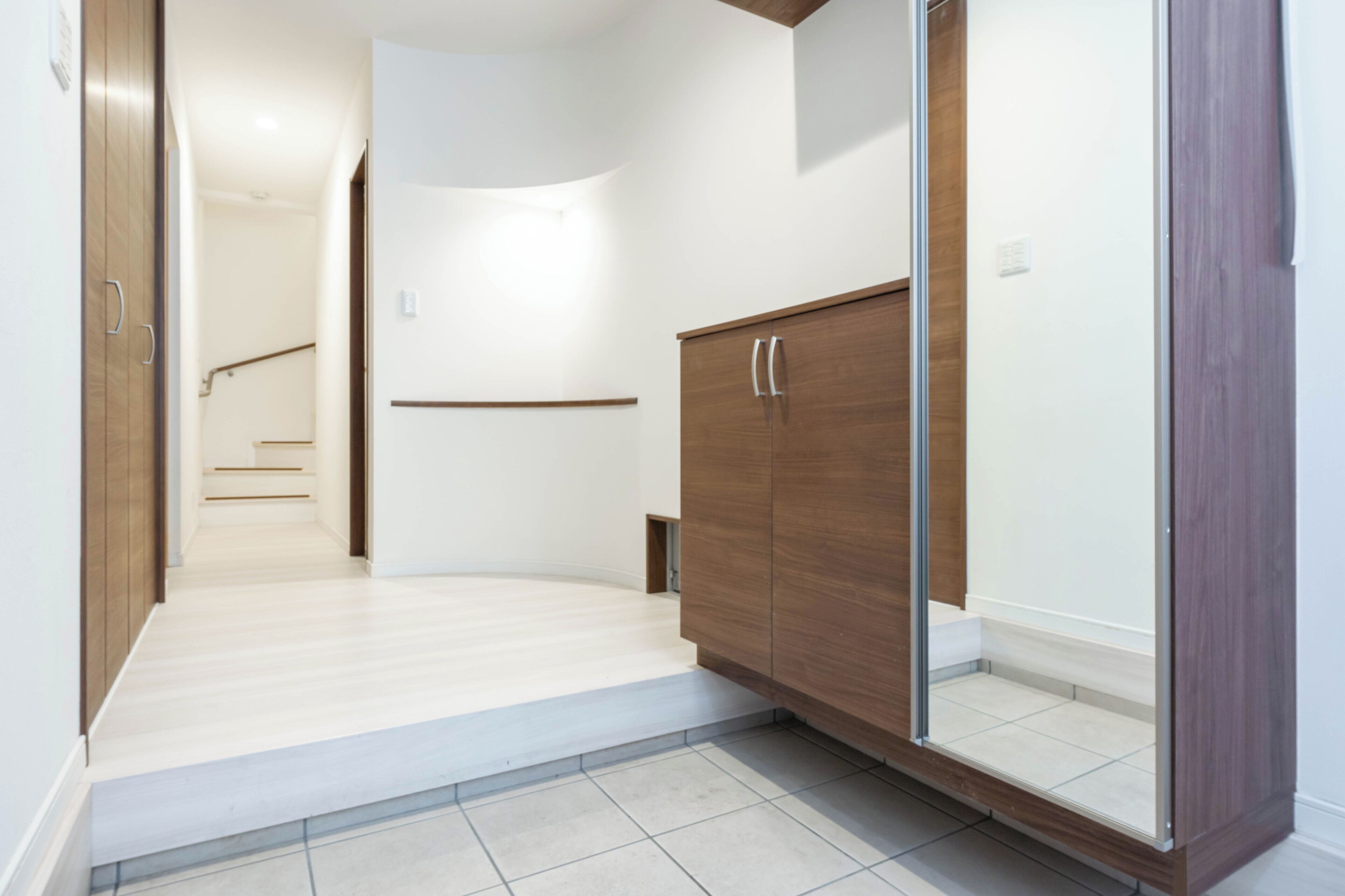 A hallway with a wooden wardrobe, a glass door, and a staircase in the background.