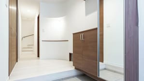 Un couloir avec une armoire en bois, une porte en verre et un escalier en arrière-plan.