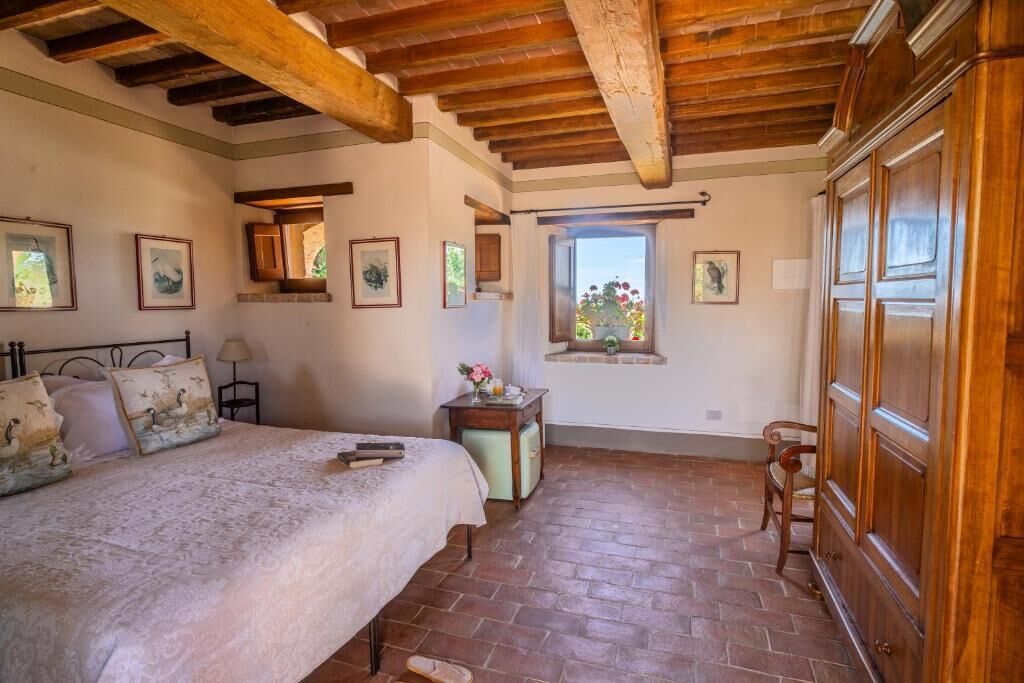 Ein Schlafzimmer mit einem großen Bett, Holzbalken, einem Fenster mit Blick und einem hölzernen Kleiderschrank.