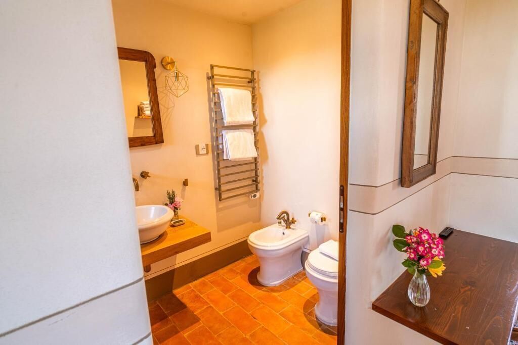 Ein Badezimmer mit Waschbecken, zwei Toiletten, einem Handtuchhalter und einem Spiegel.