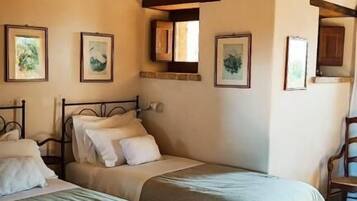 A bedroom with two beds, wooden beams on the ceiling, and framed artwork on the walls.