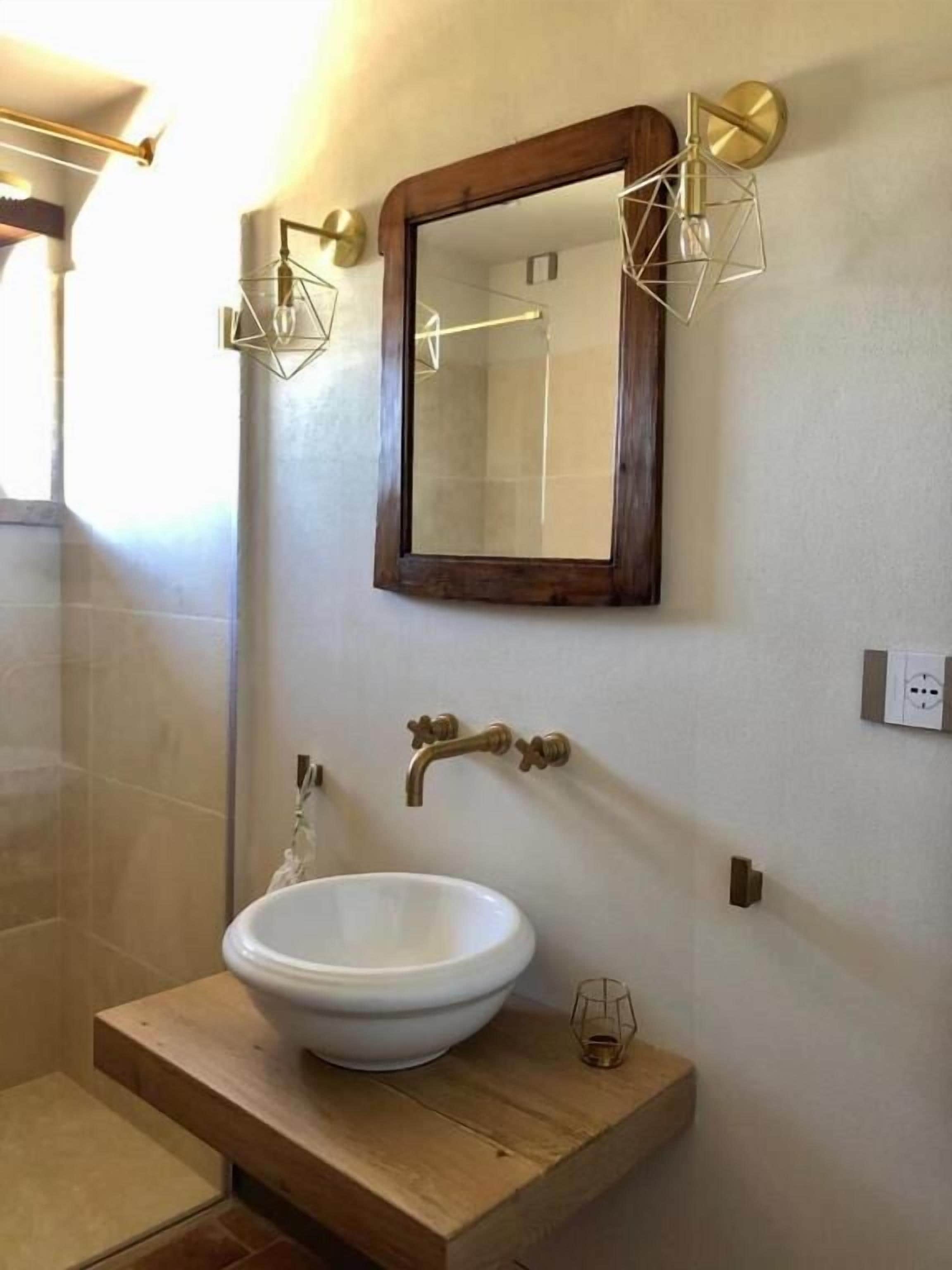 A bathroom with a large mirror, a white sink, and a wooden vanity.